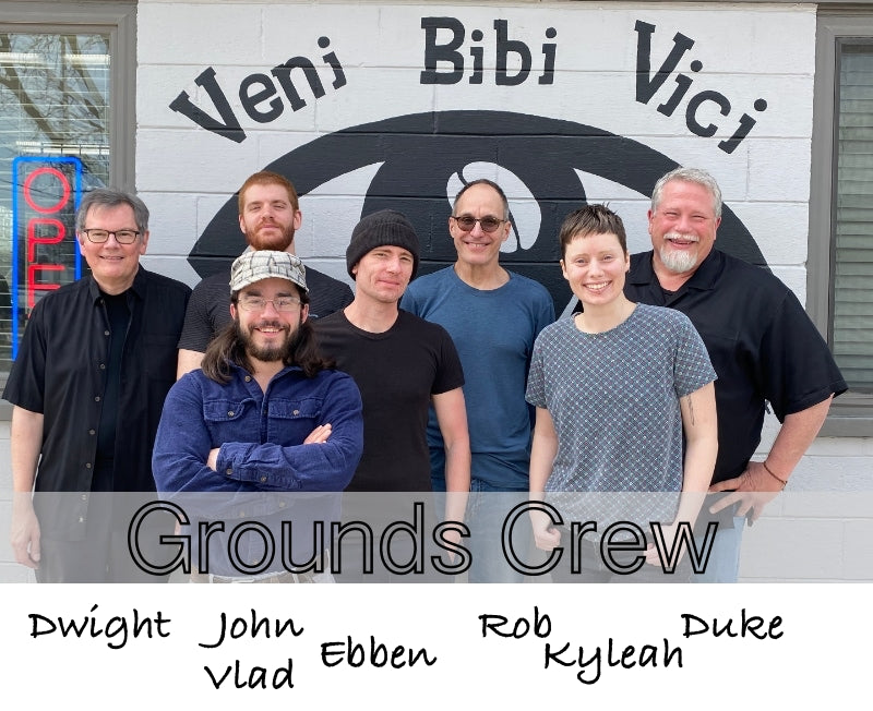 Seven members of the I Have a Bean Grounds Crew standing in front of a mural with the words Veni Bibi Vici