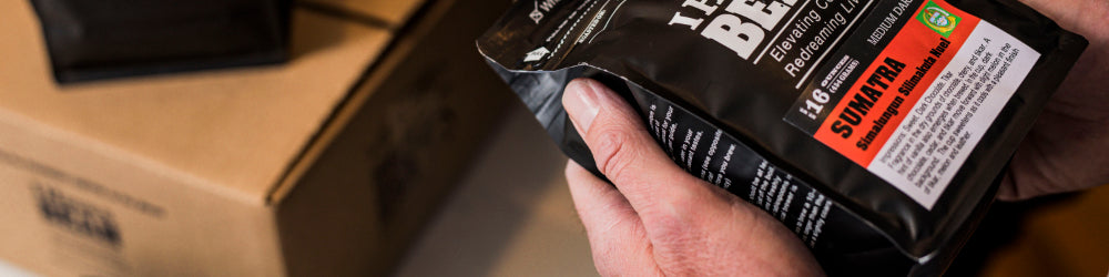 White hand holding an I Have a Bean Sumatra coffee bag