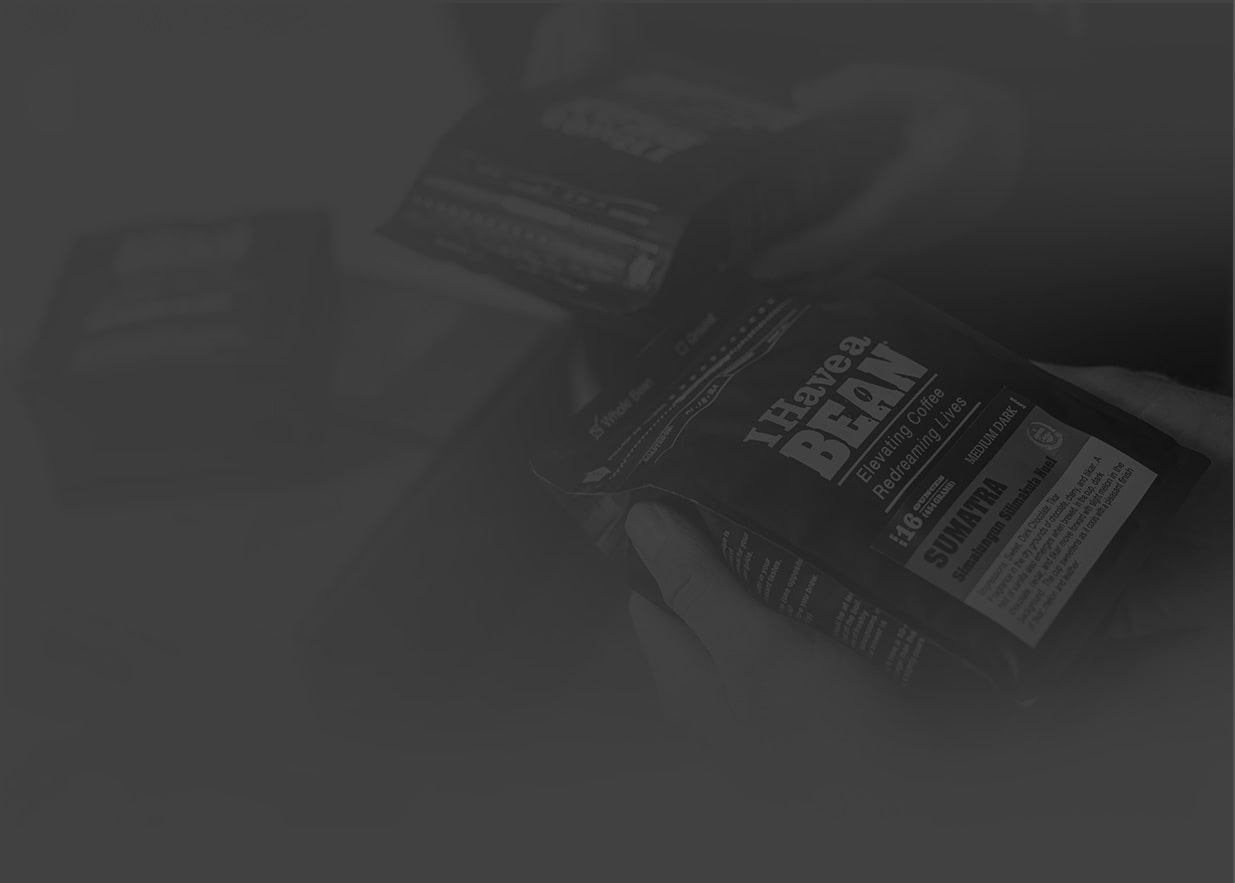 Faded photo showing two people holding an I Have a Bean coffee bag together