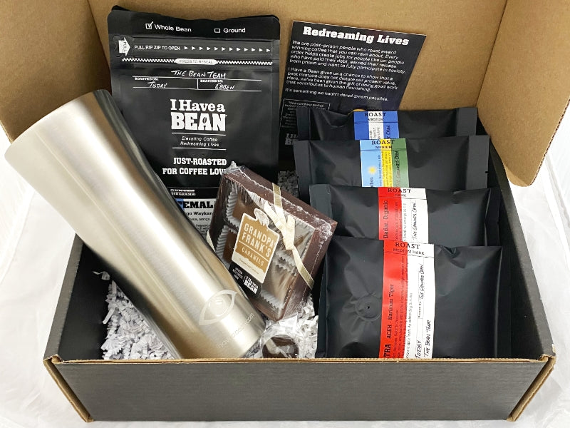 Inside of the Roast Masters Gift Box with coffee samples, silver travel mug and caramels